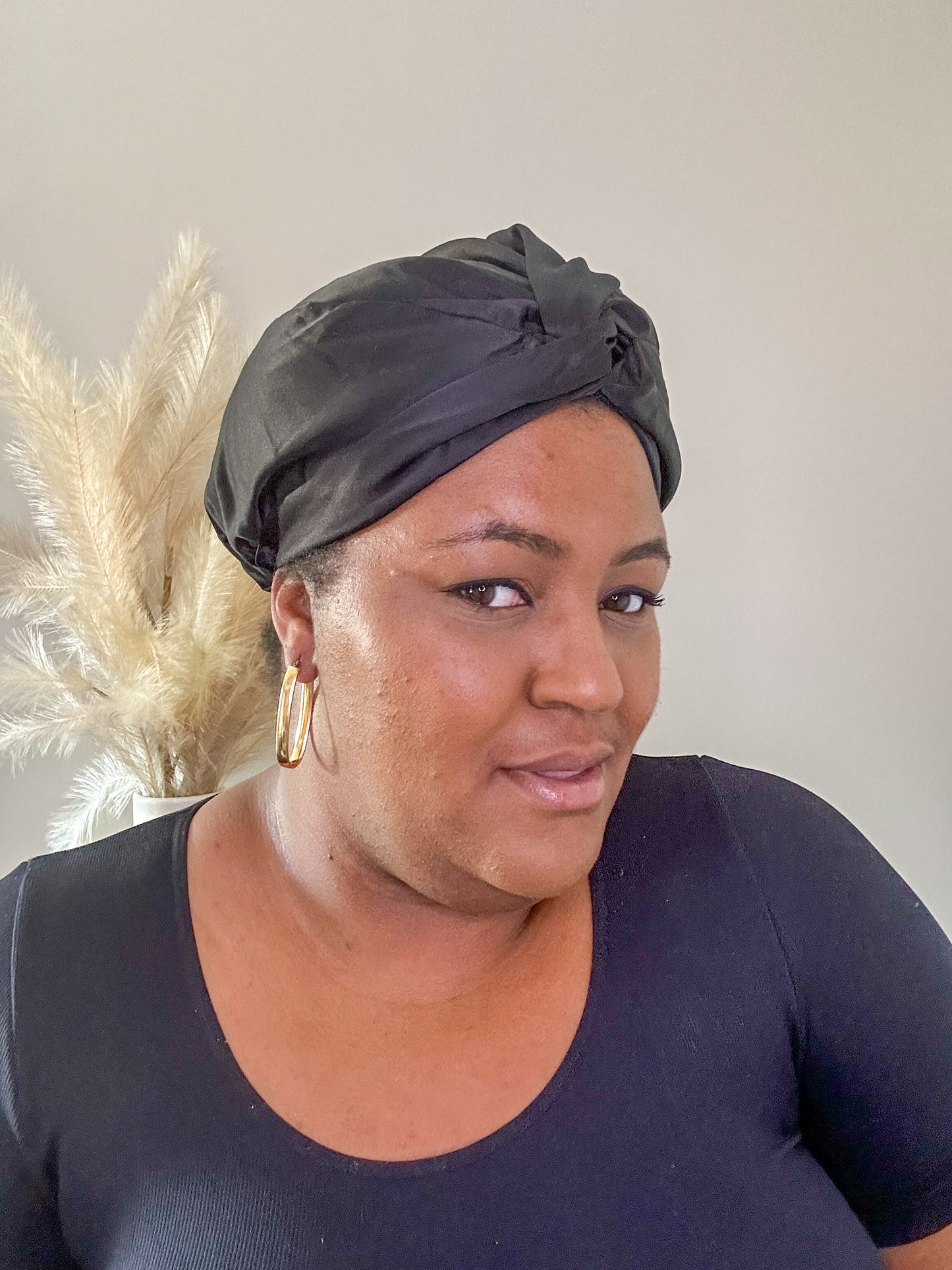 silk bonnet with twist detail at front - on black model with pampas grass in background