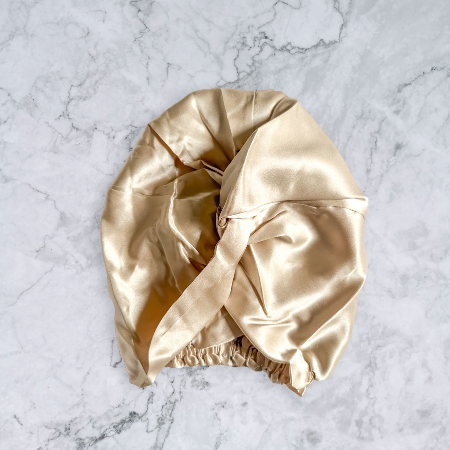silk bonnet with twist detail to front elastic to back - champagne nude front view