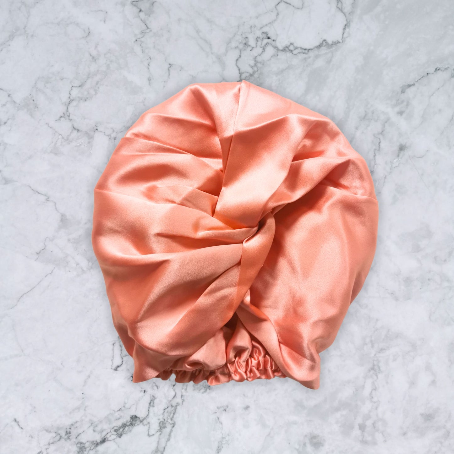 silk_twist_bonnet_coral_orange_pink on marble background