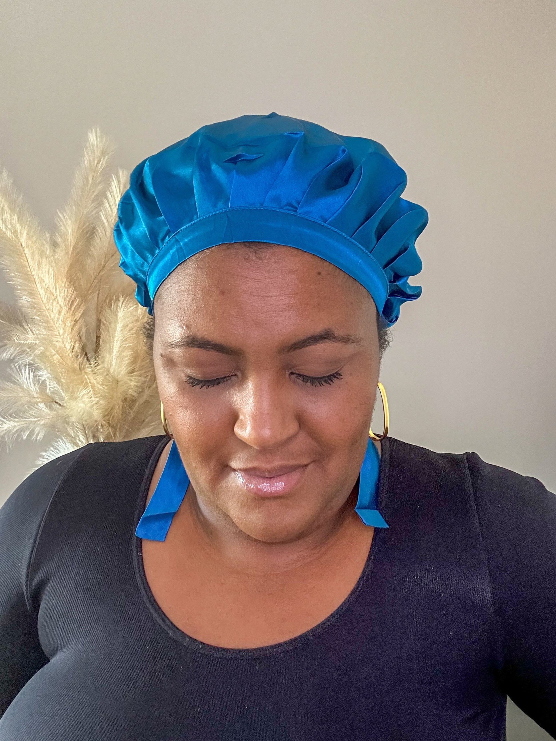 silk bonnet with hair wrap ties - peacock teal colour on black female model eyes closed with natural background