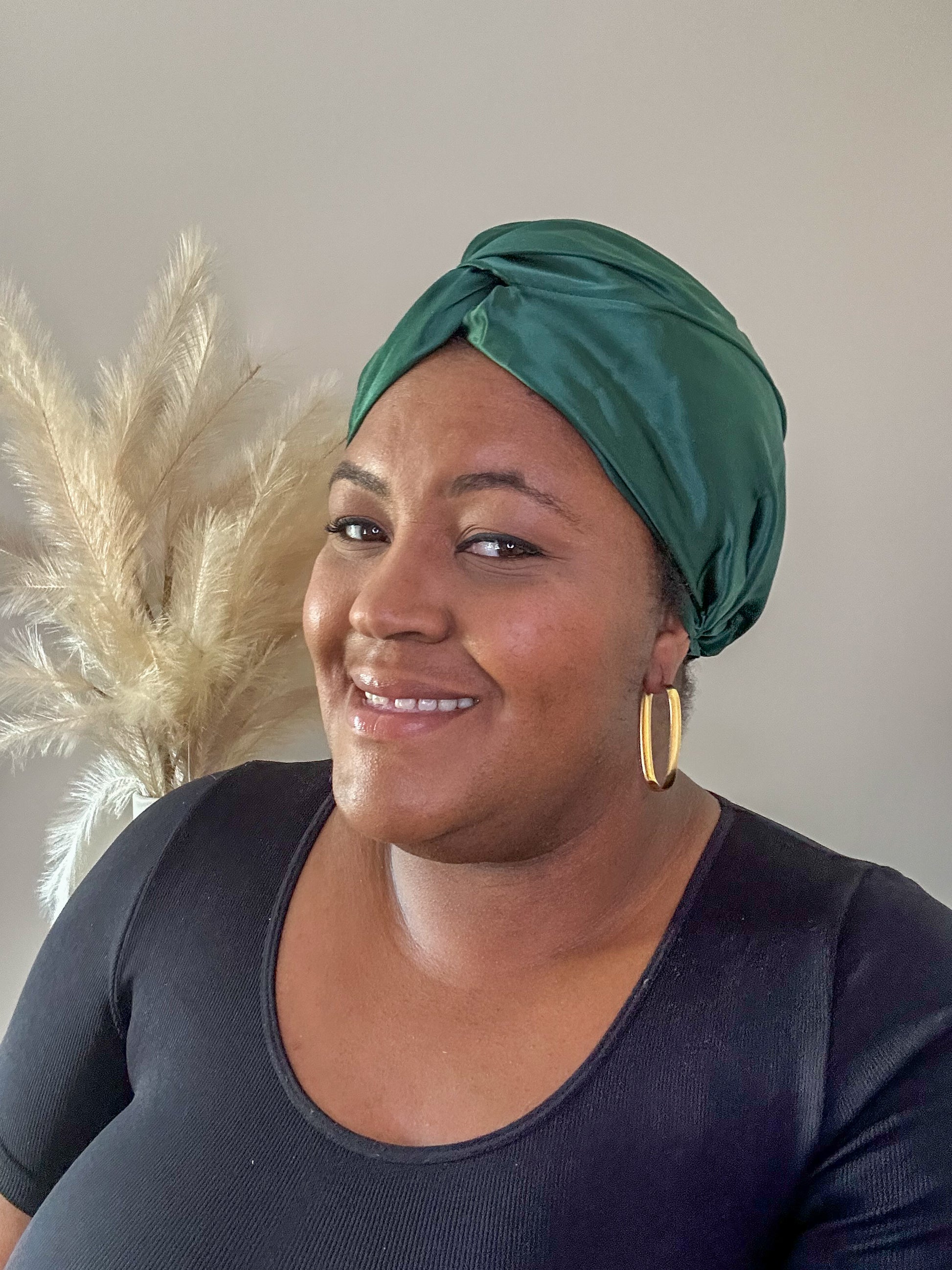 silk bonnet with twist detail at front - bottle green on black model with pampas grass in background