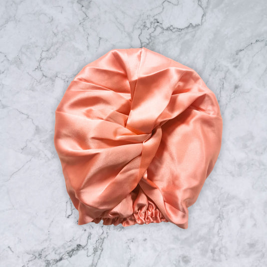silk_twist_bonnet_coral_orange_pink on marble background