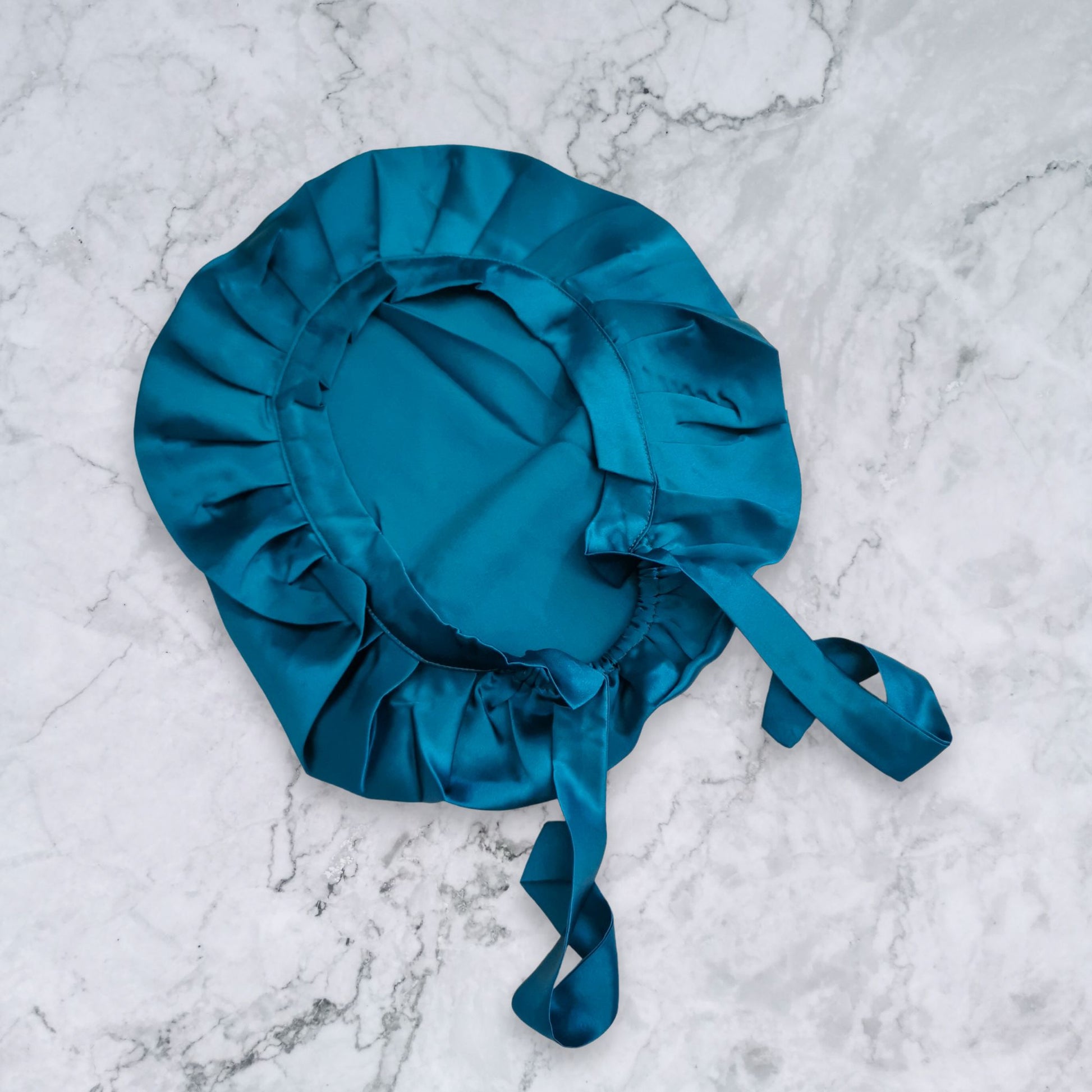 silk bonnet with hair wrap ties - peacock teal colour on marble background