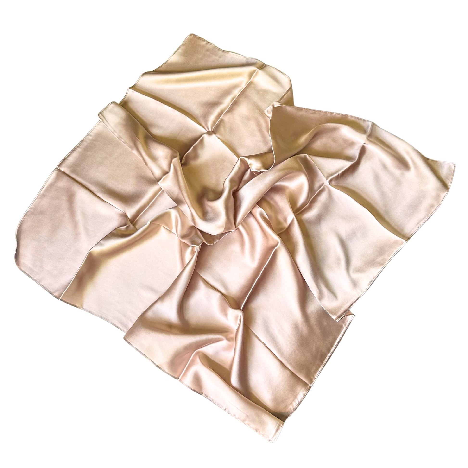 A light beige silk hair scarf , draped in soft folds against a solid white background.