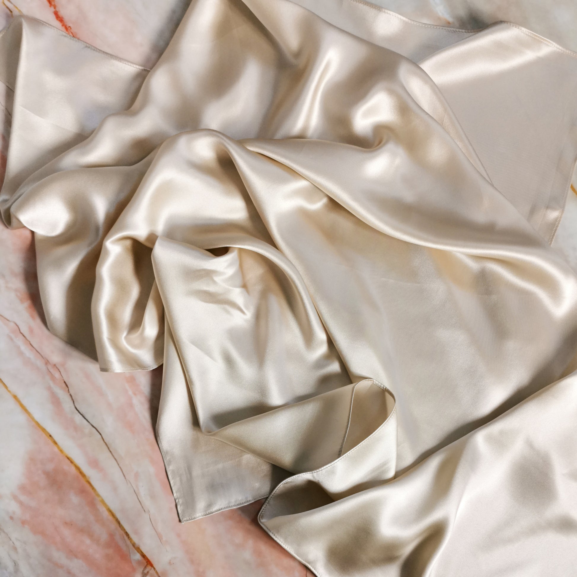 Champagne nude mulberry silk hair scarf on marble background 